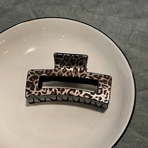 Detail of leopard print hair claw clip with square hollow design on ceramic plate