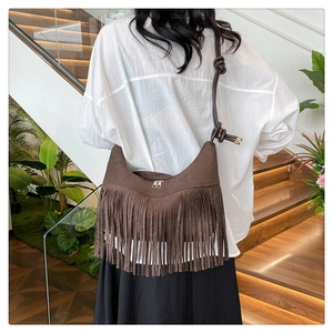 Détail d'un sac demi-lune en daim marron foncé avec de longues franges et une bandoulière nouée