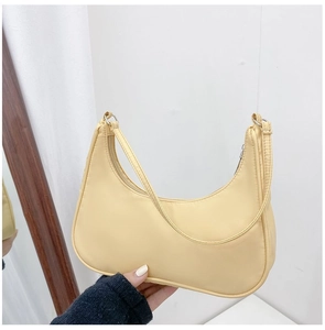 Detail of a beige nylon hobo bag featuring a top zipper and slender shoulder strap