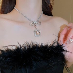 Détail d'un collier en argent avec un gros pendentif gemme rose et nœud en diamants