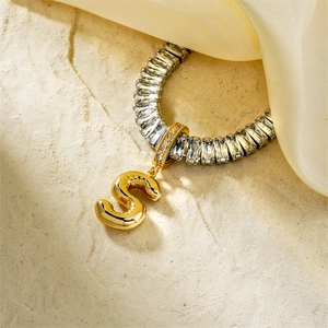 Detailed close-up of a silver necklace with a gold S-letter pendant and zircon inlay