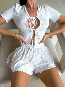Dettaglio pigiama in pizzo bianco con ritagli geometrici e bordi a volant eleganti