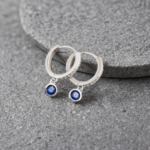 Macro shot of 925 sterling silver hoop earrings with dark blue zircon on stone