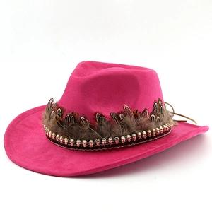 Detail of rose red suede cowboy hat with brown feathers and golden skull metal chain