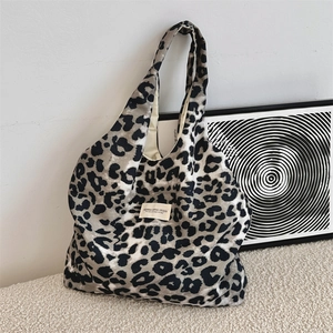 Close-up of leopard print canvas tote bag with brand label on a textured white rug