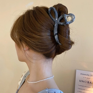 Detailed close-up of dark grey marble patterned acetate hair claw clip worn by a model
