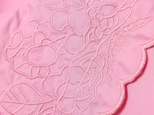 Detailed macro view of pink fabric with intricate floral embroidery on the sleeve