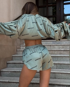 Back view of sage green satin lounge set with black logo print on stairs