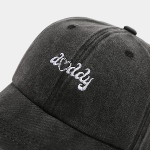 Macro view of white daddy embroidery with a heart on a black washed cotton baseball cap