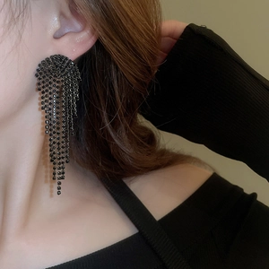 Close-up of long black rhinestone tassel earrings worn by a model for a luxury look