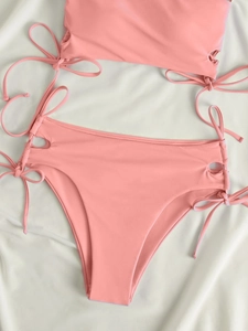 Detailed flat lay of coral pink high-waisted bikini with side drawstring hollow details