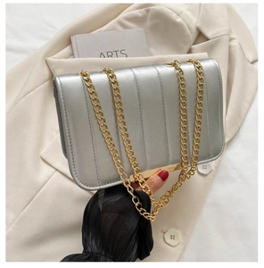 Detail of silver crossbody bag with gold chain strap and textured stripe stitching