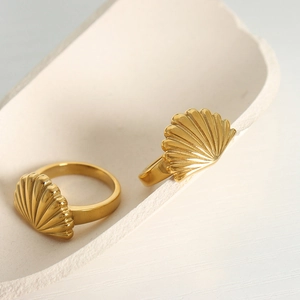 Elegant gold-plated stainless steel scallop shell rings displayed on a ceramic tray