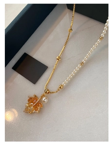 Detail of maple leaf necklace with orange crystals, gold chain and elegant pearls