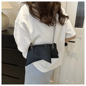 Modern black geometric crossbody bag with silver chain strap shown in a lifestyle view