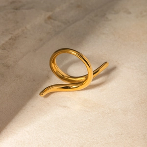 Macro shot of gold crisscross ring on textured stone with soft shadow detail