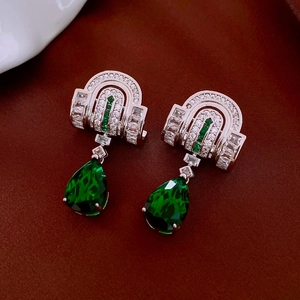 Detail of silver stud earrings featuring green teardrop zircon and luxury zircon inlay