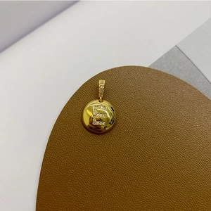 Macro detail of 18K gold plated letter E apple pendant with shimmering cubic zirconia