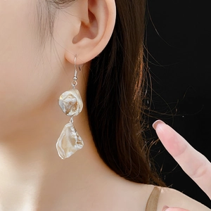 Détail de boucles d'oreilles en coquillage irrégulier avec crochets en argent sur un mannequin