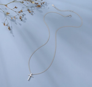 Close-up of S925 sterling silver cross pendant necklace with adjustable chain on blue background