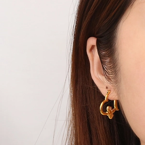 Detailed view of a golden heart hoop earring with a 3D bee accent worn on ear