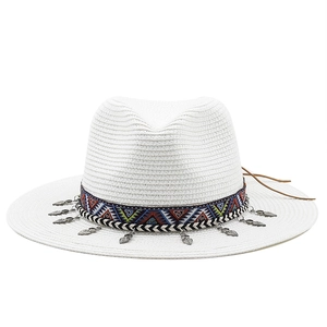 Détail du chapeau de paille blanc avec ruban ethnique et pendentif feuille argentée