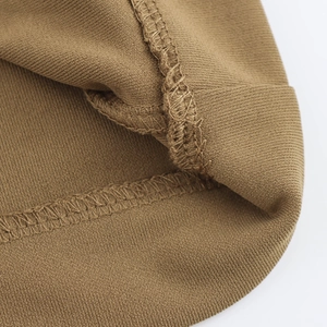 Macro shot of brown knit dress fabric texture showing precise stitching and hem details