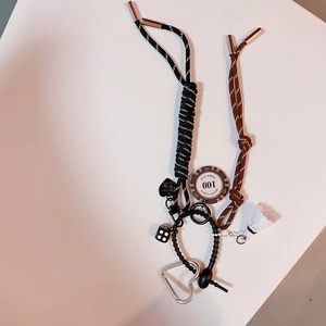 Détail de porte-clés tressés noir et marron avec dés et pendentif jeton de poker