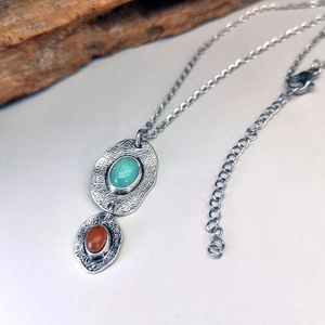 Macro detail of bohemian hammered silver necklace with turquoise and red stone pendants