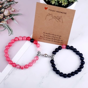 Macro view of magnetic heart bead bracelets for couples with pink and black stones