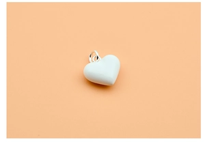 Macro detail of a white heart pendant with silver bail on an orange background