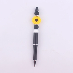 Close-up of a DIY beadable pen featuring a yellow sunflower and black silicone beads