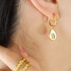 Elegant gold avocado-shaped hoop earrings with white shell inlay on model's ear