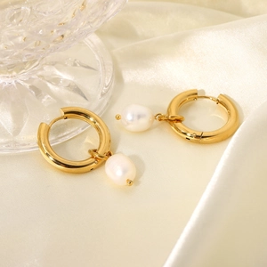 Macro shot of 18k gold plated hoop earrings with elegant pearl pendants on silk fabric