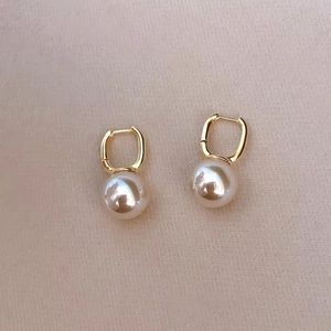 Detailed close-up of gold square hoop earrings with elegant hanging pearl pendants