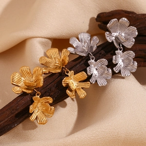 Detailed view of gold and silver textured petal earrings displayed on a rustic branch