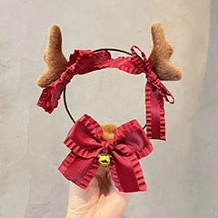 Detail of Christmas reindeer antler headband with brown plush, red bow and gold bell