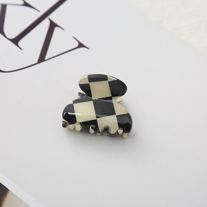 Close-up of checkerboard hair claw clip with glossy finish on a white background