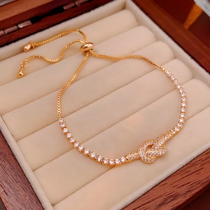 Macro shot of gold-plated knot bracelet with white zircons in a luxury jewelry box