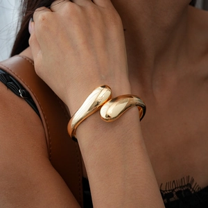 Macro shot of liquid teardrop gold cuff bracelet with polished mirror finish on wrist