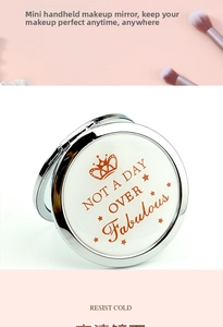 Detail of a portable round metal folding makeup mirror with crown print and text