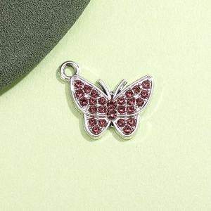 Macro di un ciondolo a farfalla d'argento con strass rosa per creazione di gioielli fai da te