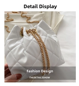 Detailed view of white quilted bucket bag with gold chain strap and pearl charm