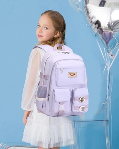 Close-up of a purple school backpack showing side mesh pocket and decorative badges