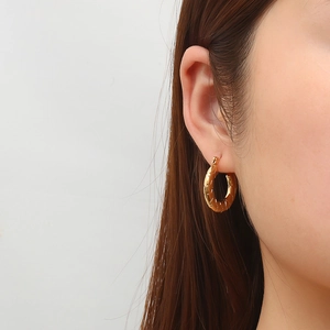 18K gold-plated stainless steel hoop earrings with textured finish on female model