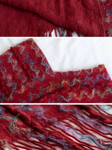 Détail d'un châle en tricot rouge avec motifs à vagues colorées et textures à franges