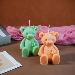 Detailed view of mint green and orange bear candles with floral and heart relief patterns