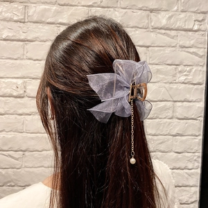 Detail of purple organza bow hair claw with elegant pearl tassel on gold metal clip
