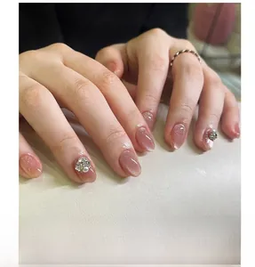 Detail of pink cat eye press-on nails with pearl and rhinestone accents and silver ring