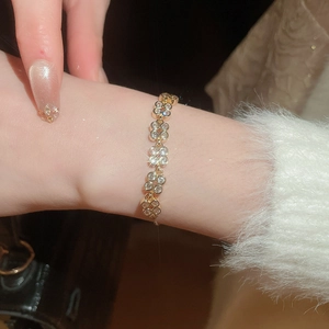 Close-up of a gold flower bracelet with sparkling zircons worn on a wrist with soft sweater